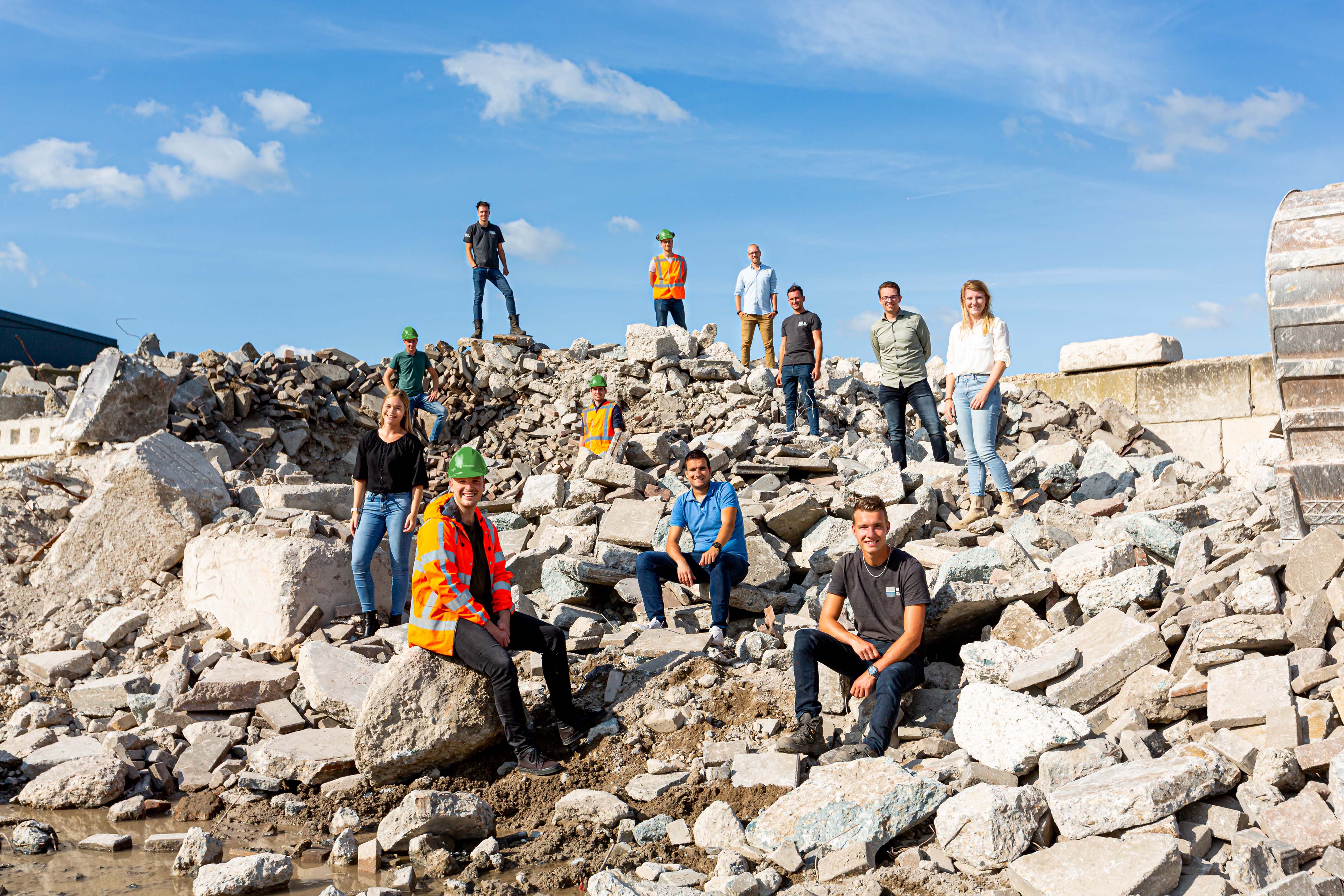 AW Groep jongeren, medewekers poseren in een hoop betonpuin